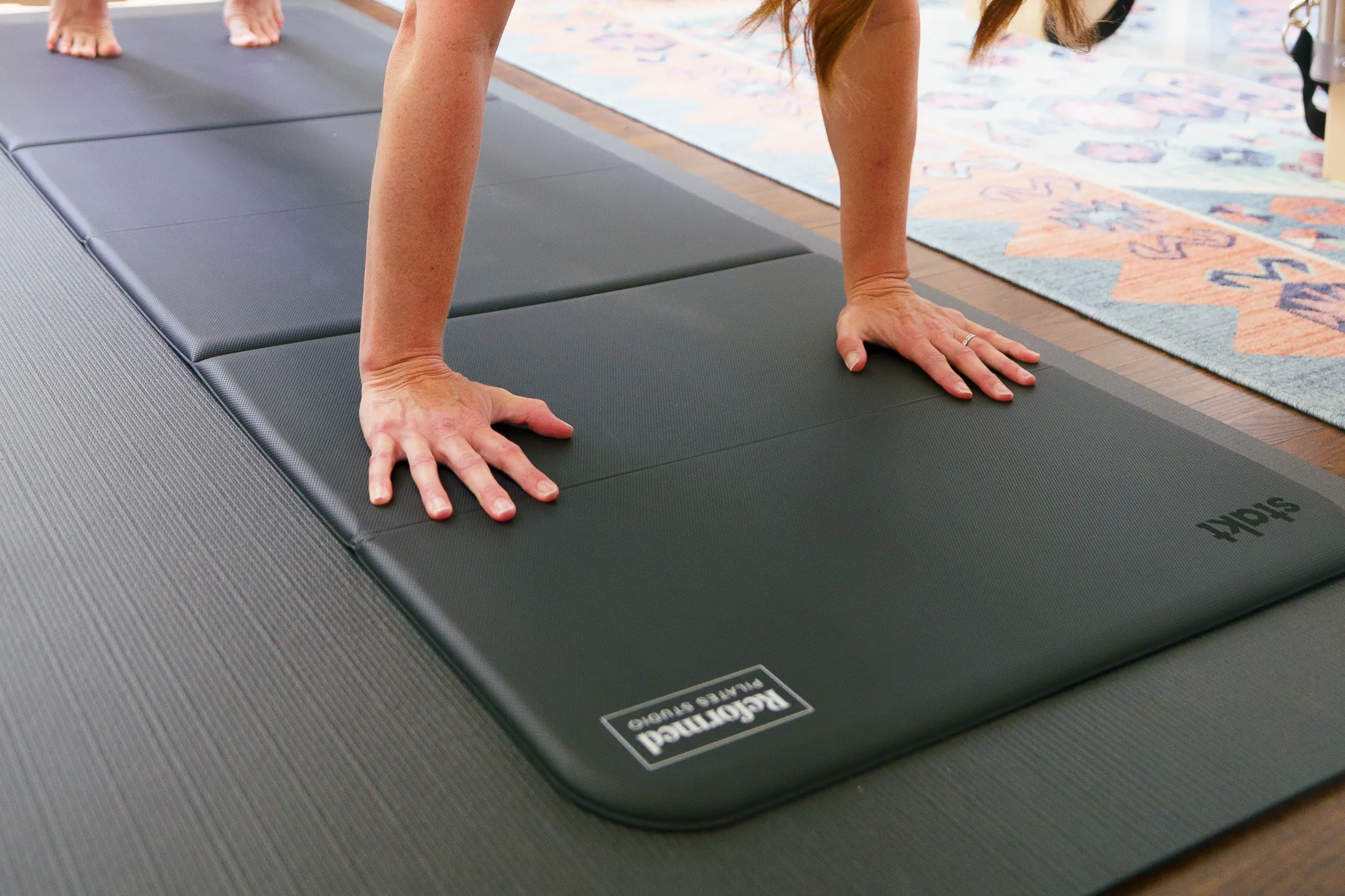 Hands pressing into a Reformed Pilates Studio mat