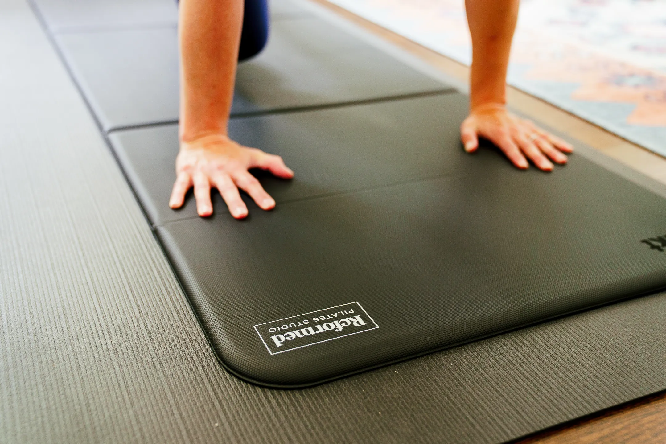 Close-up of hands on a Reformed Pilates Studio mat